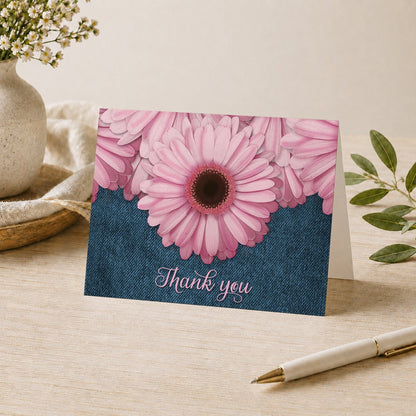 Rustic Pink Daisy and Denim Thank You Card shown on a tabletop with a vase, plants, and a pen.