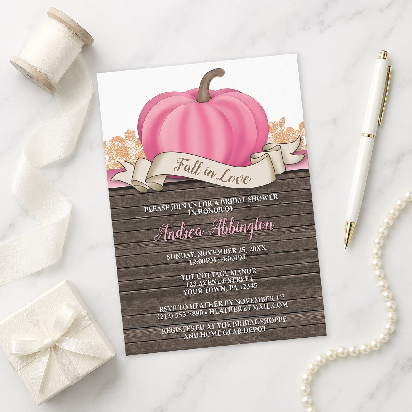 Rustic Pink Pumpkin Fall in Love Bridal Shower Invitation shown on a marble surface with a white gift box, pen, ribbon, and pearls.