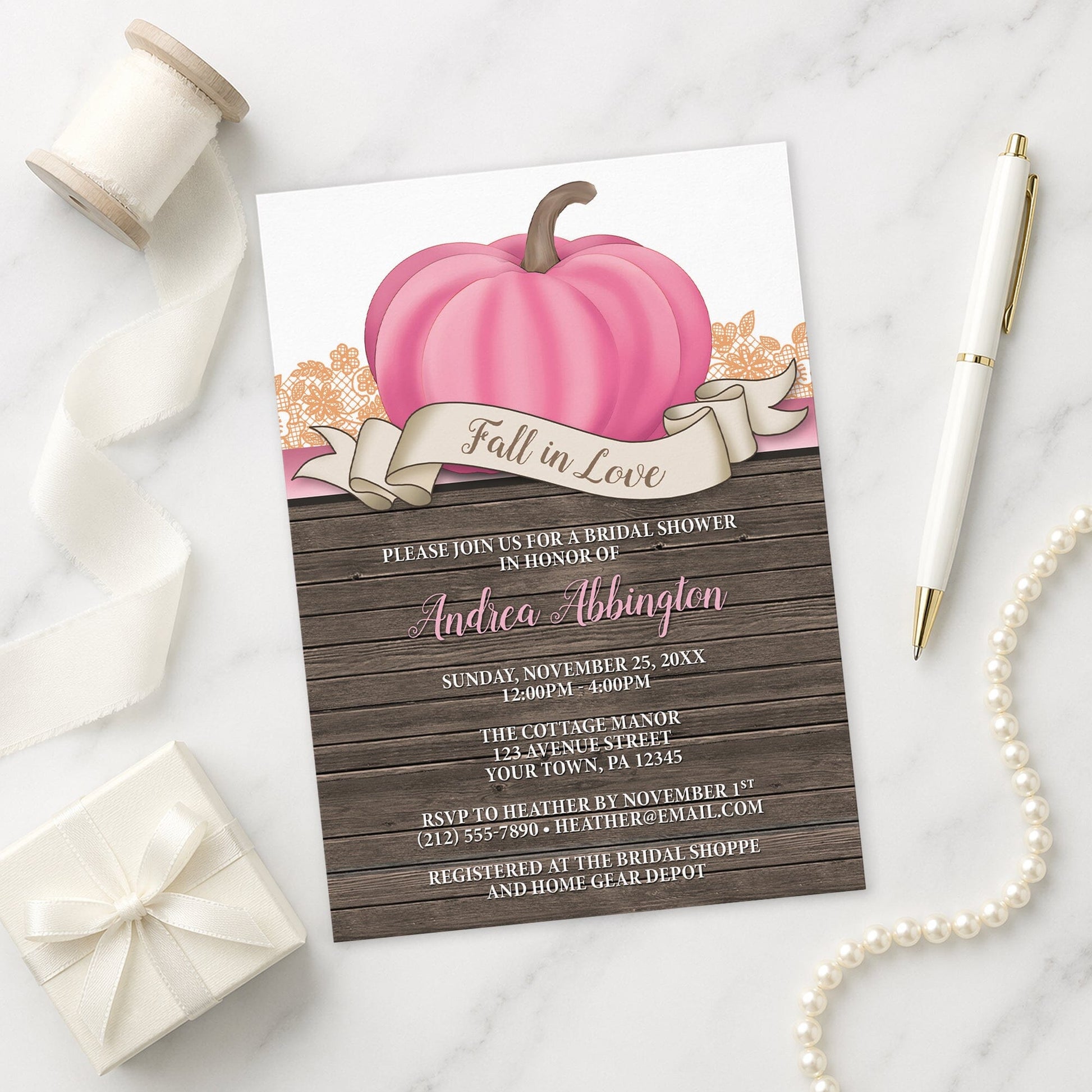 Rustic Pink Pumpkin Fall in Love Bridal Shower Invitation shown on a marble surface with a white gift box, pen, ribbon, and pearls.