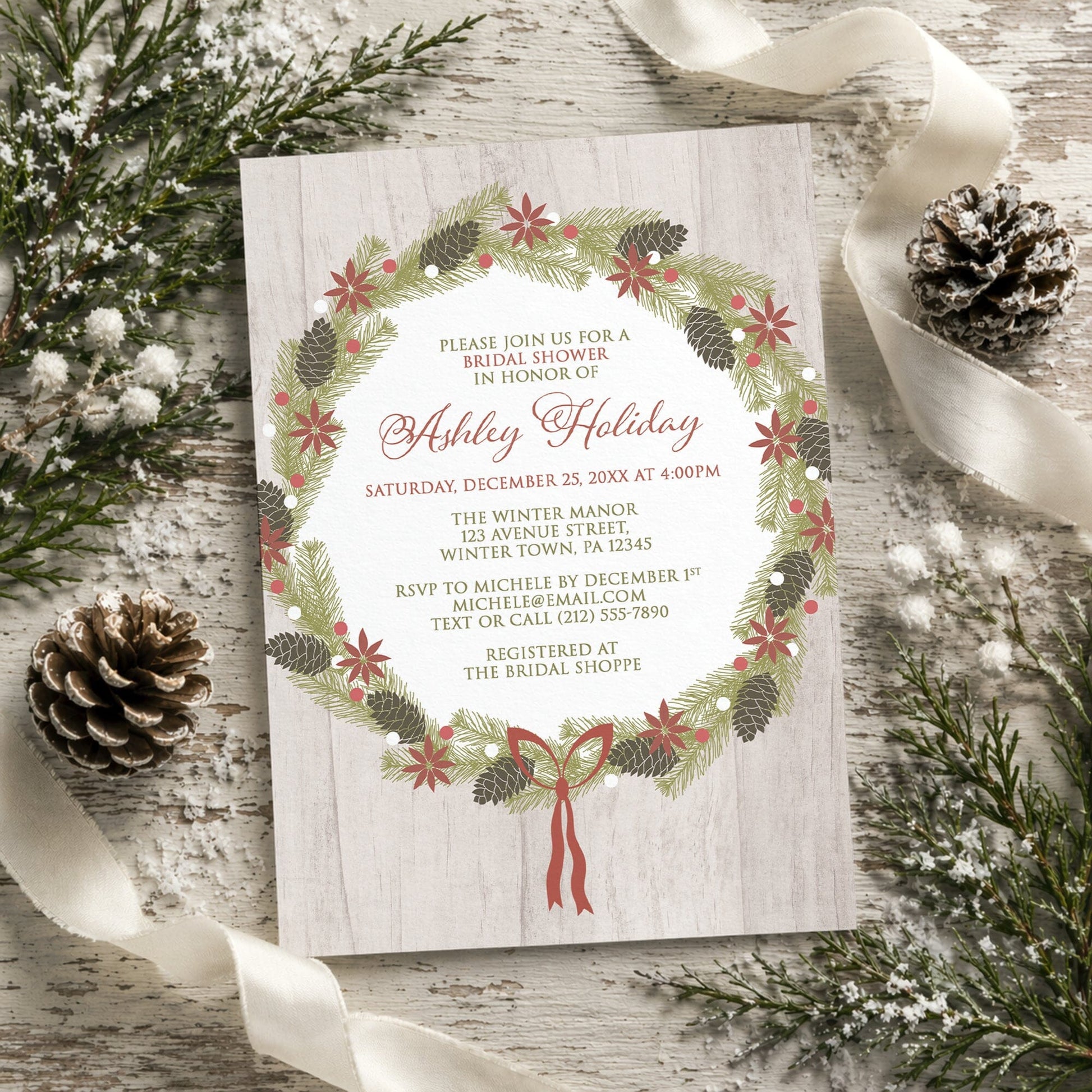Rustic Poinsettia Pine Cone Wreath Bridal Shower Invitation on a rustic wood surface with winter pine cones and ribbon.