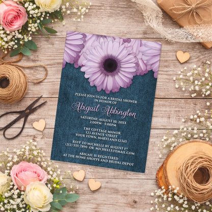 Rustic Purple Daisy Denim Bridal Shower Invitation shown on a country wooden surface with spring and summer flowers, small wood hearts, lace ribbon, and twine.