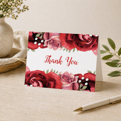 Rustic Red Pink Rose Green White Thank You Card shown on a desk with a vase, plants, and a pen.