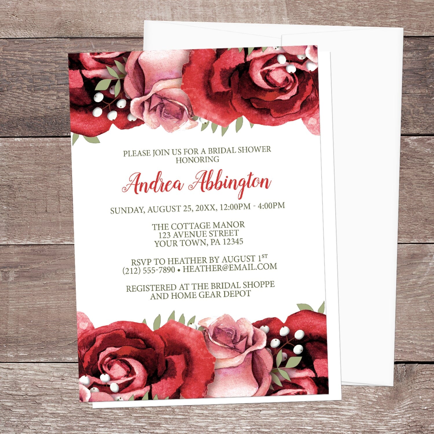 Rustic Red Pink Rose Green White Bridal Shower Invitation shown on a wooden surface with a white envelope.