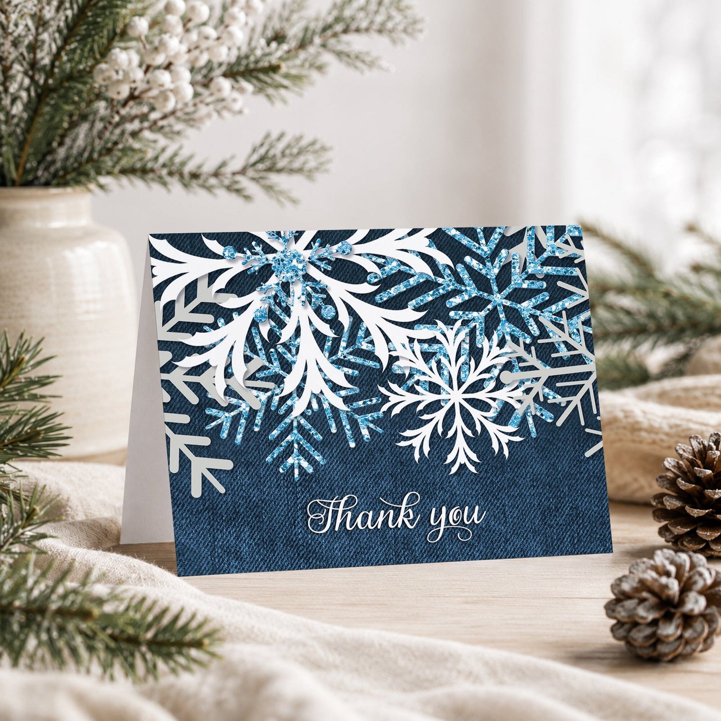 Rustic Snowflake Denim Winter Thank You Card shown on a tabletop with a vase, winter greenery, and pine cones.