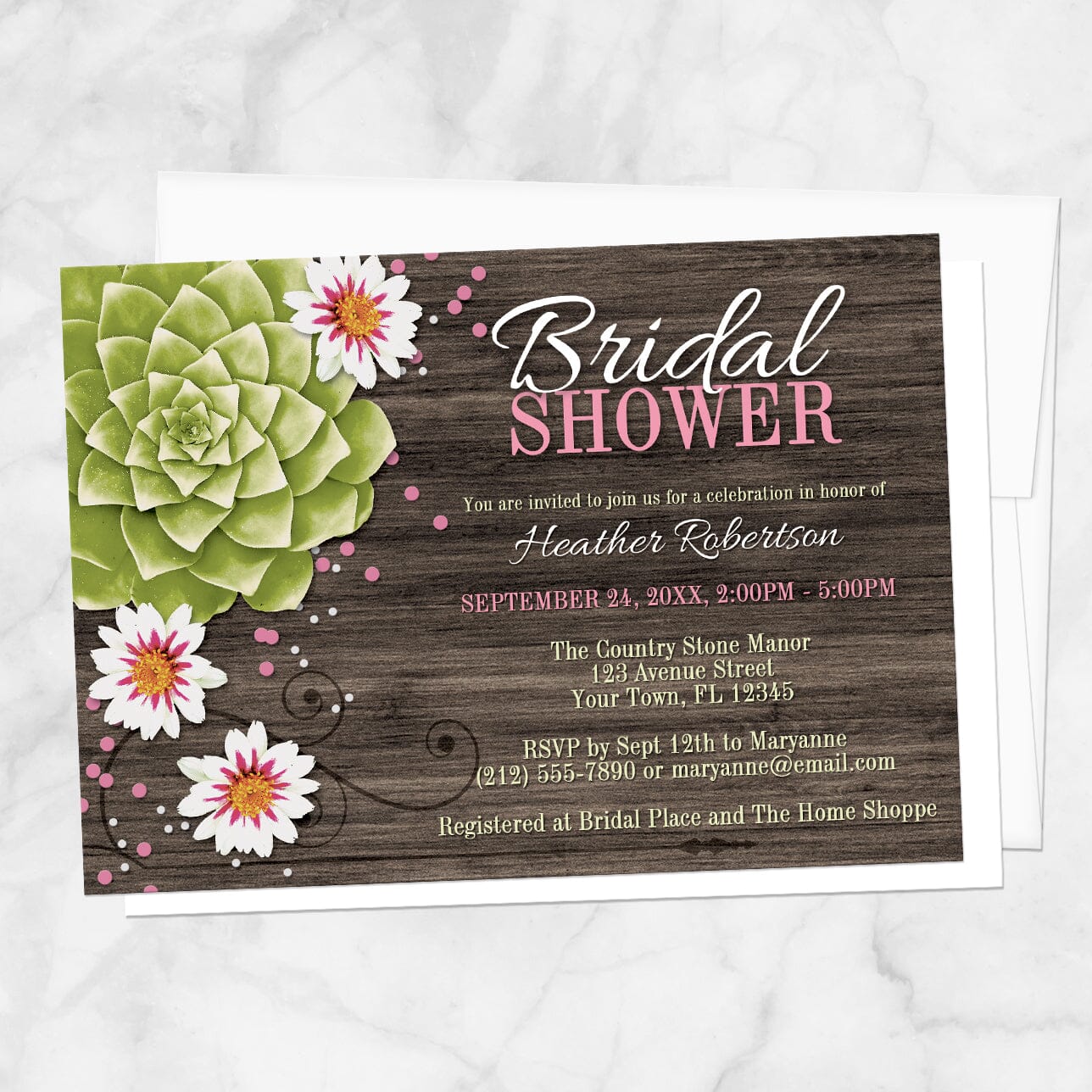 Rustic bridal shower invitation with a green succulent, white flowers, and pink and white confetti dots over a brown wood background, displayed with a white envelope on a marble surface