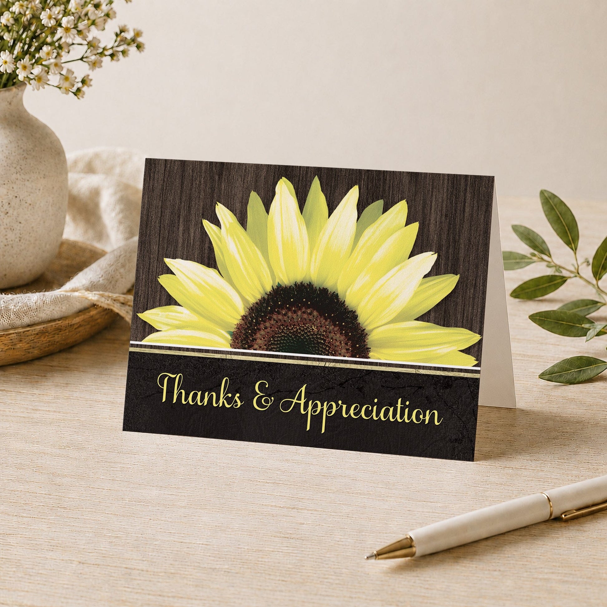 Rustic Sunflower Black Thank You Card shown on a desk with a vase, plants, and a pen.
