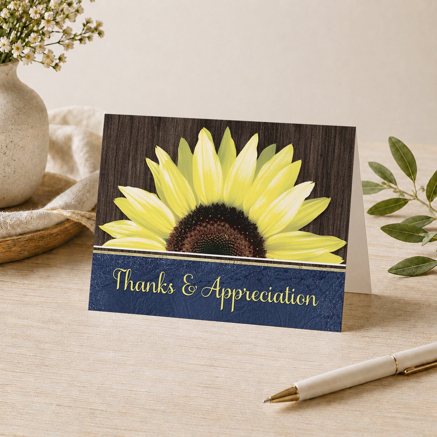 Rustic Sunflower Blue Thank You Card shown on a desk with a vase, plants, and a pen.