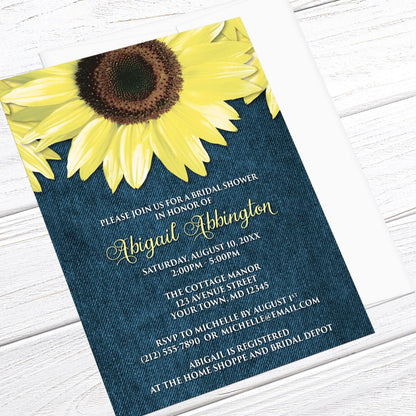 Bridal Shower invitation with large yellow sunflowers and blue denim, displayed at an angle with a white envelope on a white wood surface