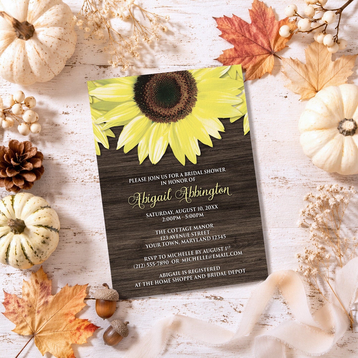 Rustic Sunflower and Wood Bridal Shower Invitation on a wooden surface with fall decorations.