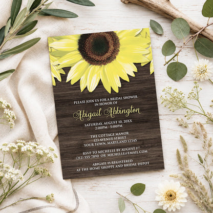 Rustic Sunflower and Wood Bridal Shower Invitation shown on a light wooden surface with spring and summer plants.