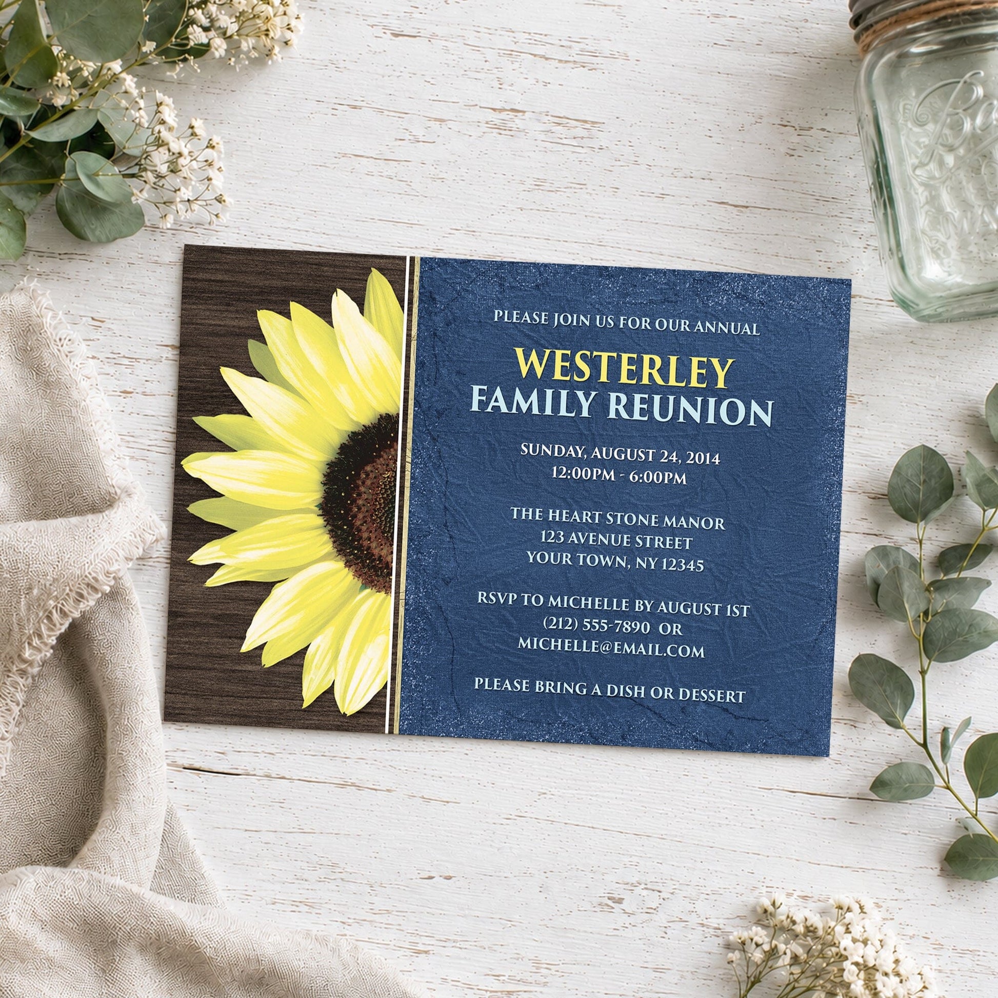 Rustic Sunflower with Blue Family Reunion Invitation shown on a light wooded surface with plants and a small mason jar.