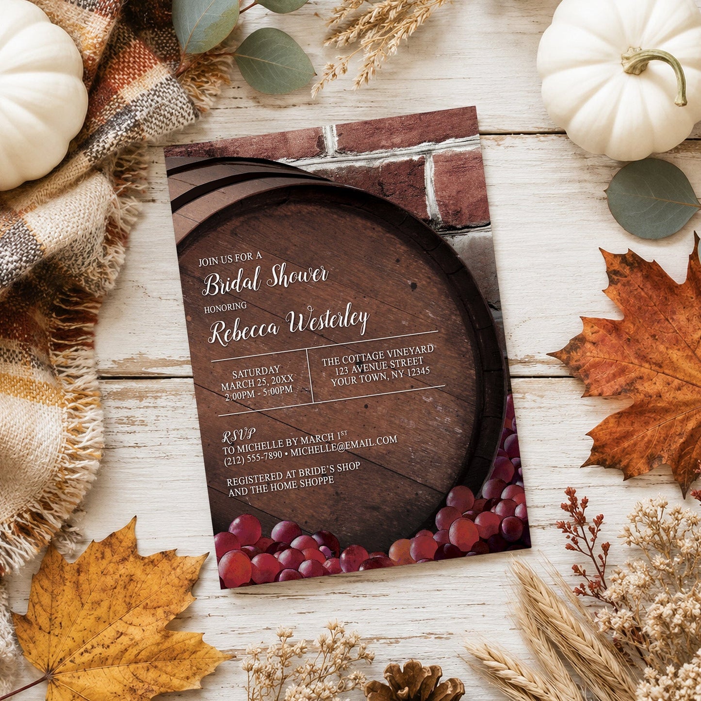 Rustic Wine Barrel Vineyard Bridal Shower Invitation shown on a light wooden surface with fall leaves and autumn decor.