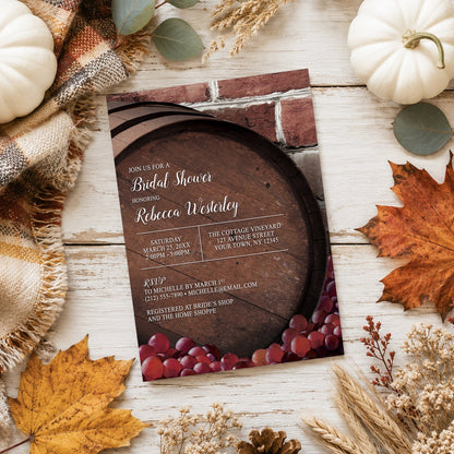 Rustic Wine Barrel Vineyard Bridal Shower Invitation shown on a light wooden surface with fall leaves and autumn decor.
