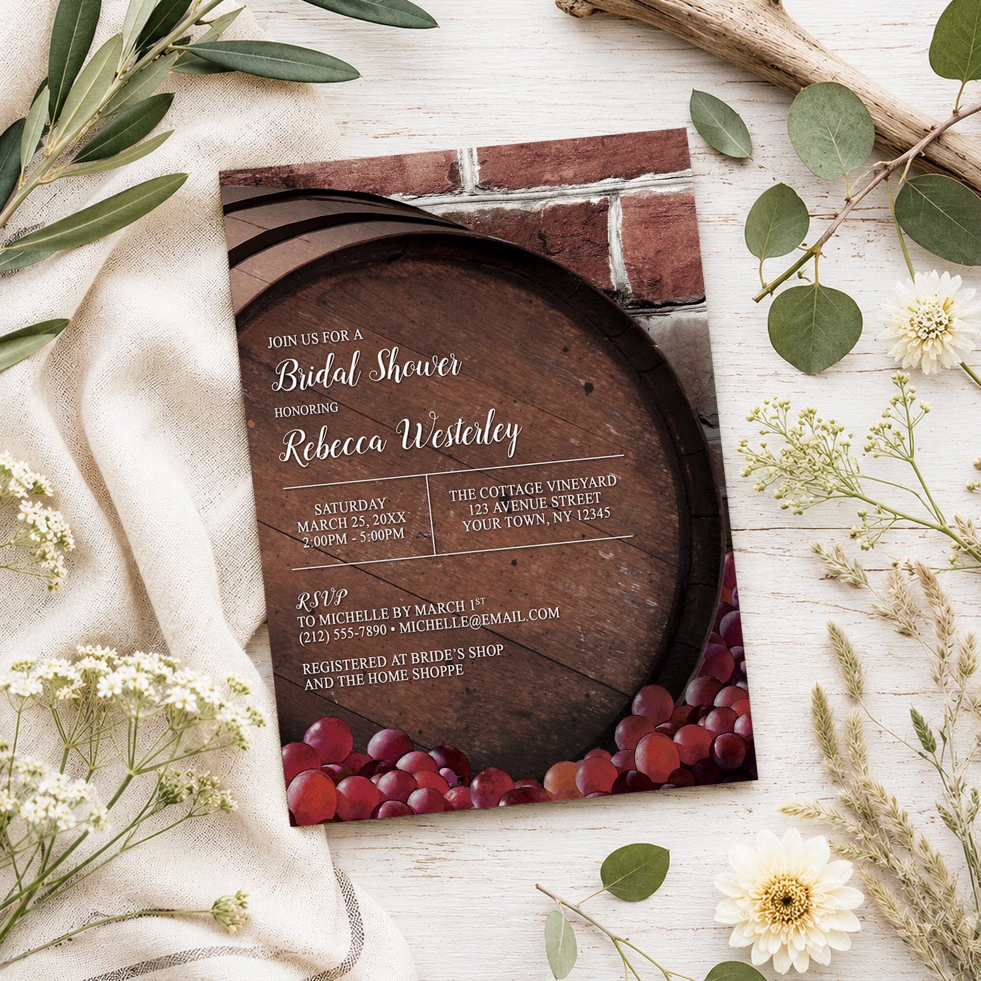 Rustic Wine Barrel Vineyard Bridal Shower Invitation shown on a light wooden surface with spring and summer plants.