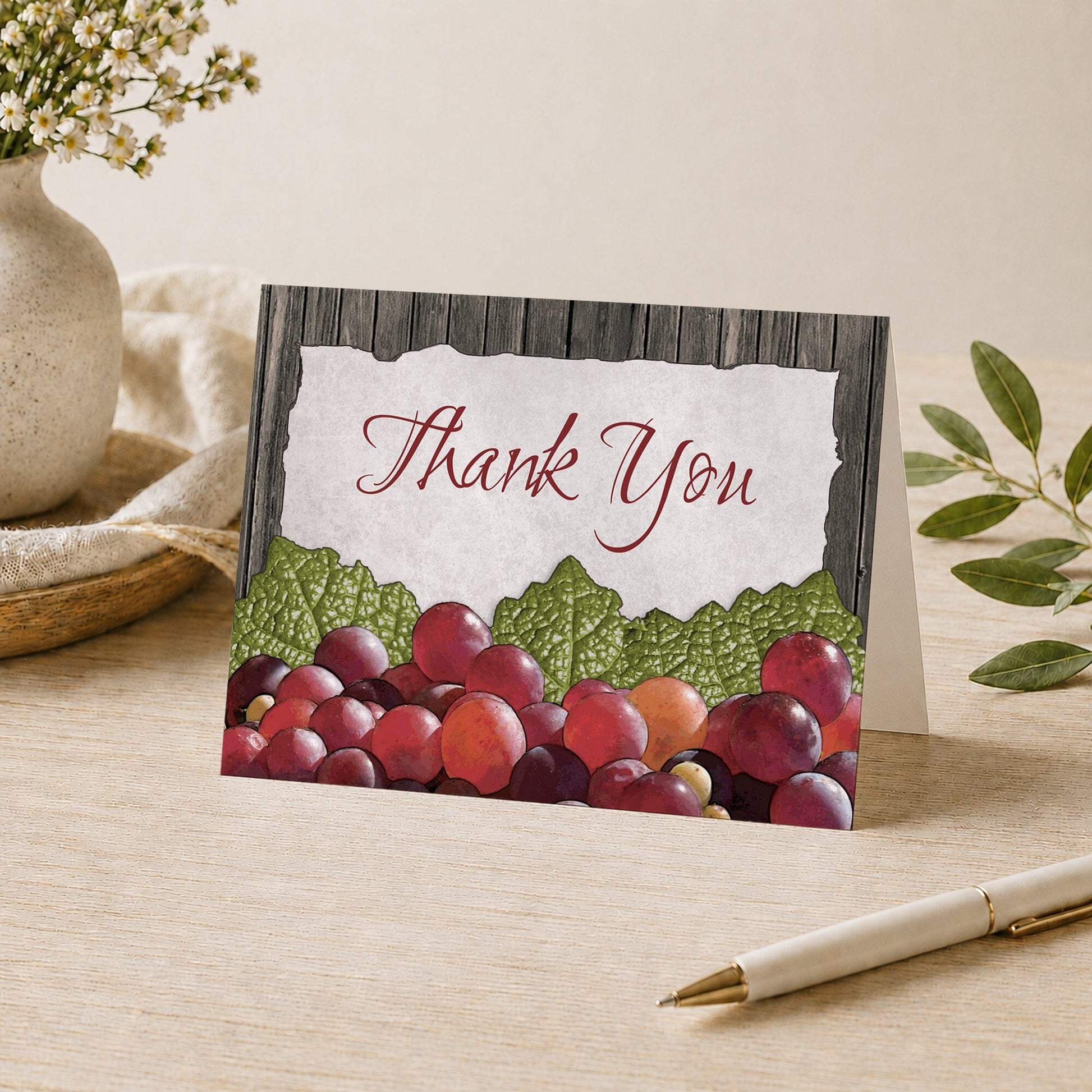 Rustic Winery Grapes Thank You Card shown on a desk with a vase, plants, and a pen.