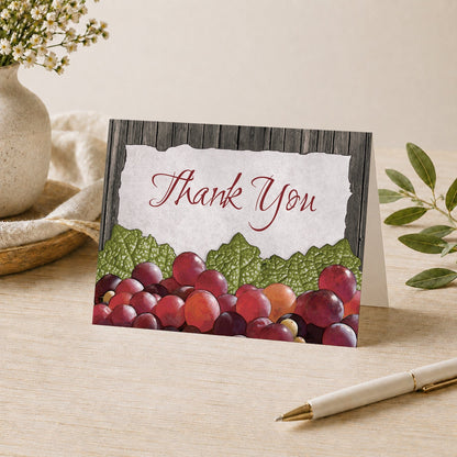 Rustic Winery Grapes Thank You Card shown on a desk with a vase, plants, and a pen.