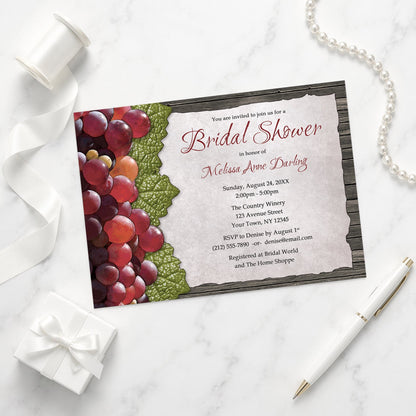 Rustic Winery Grapes and Wood Bridal Shower Invitation shown on a marble surface with a white gift box, pen, ribbon, and pearls.