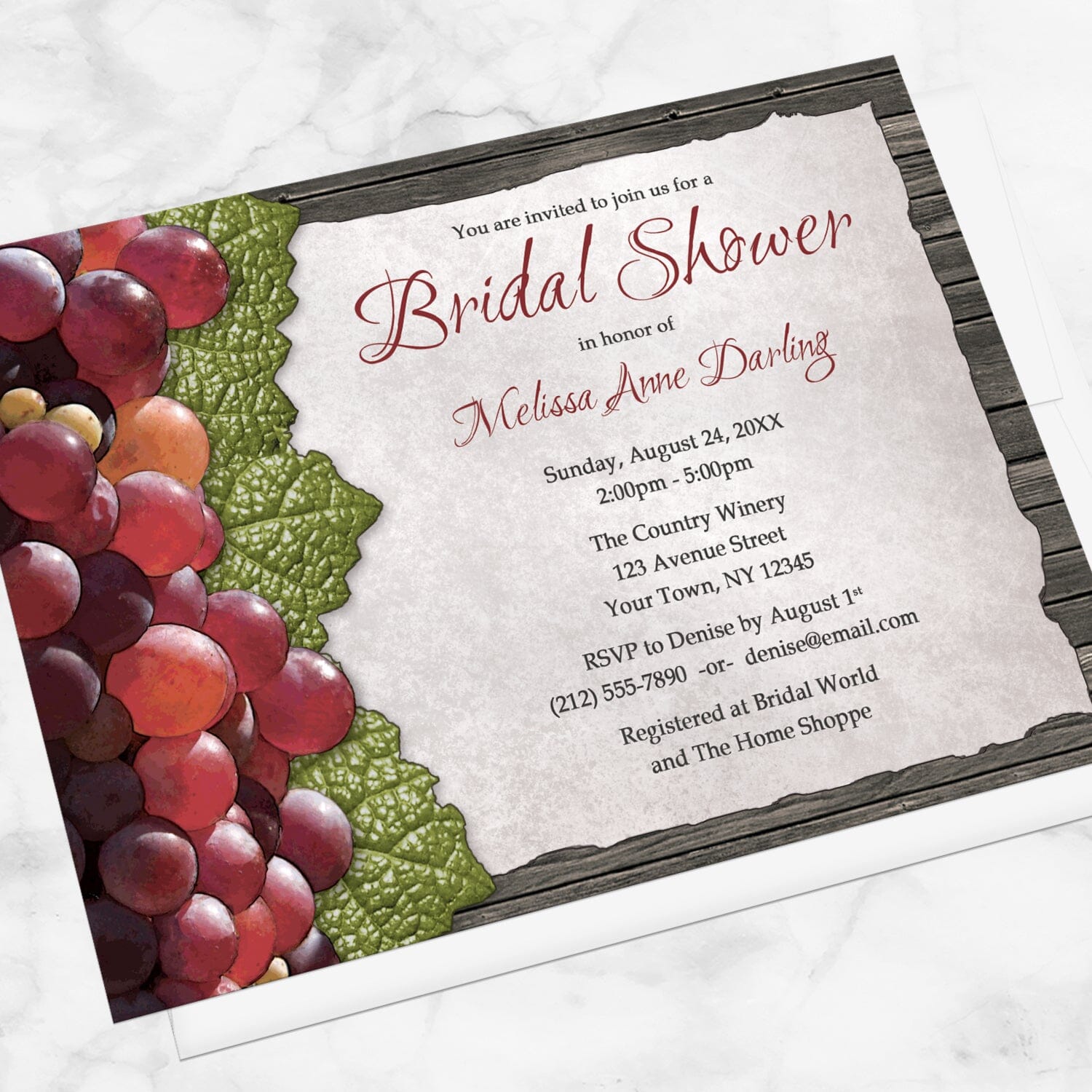 Rustic Winery Grapes and Wood Bridal Shower Invitation shown at an angle on a marble surface with a white envelope.