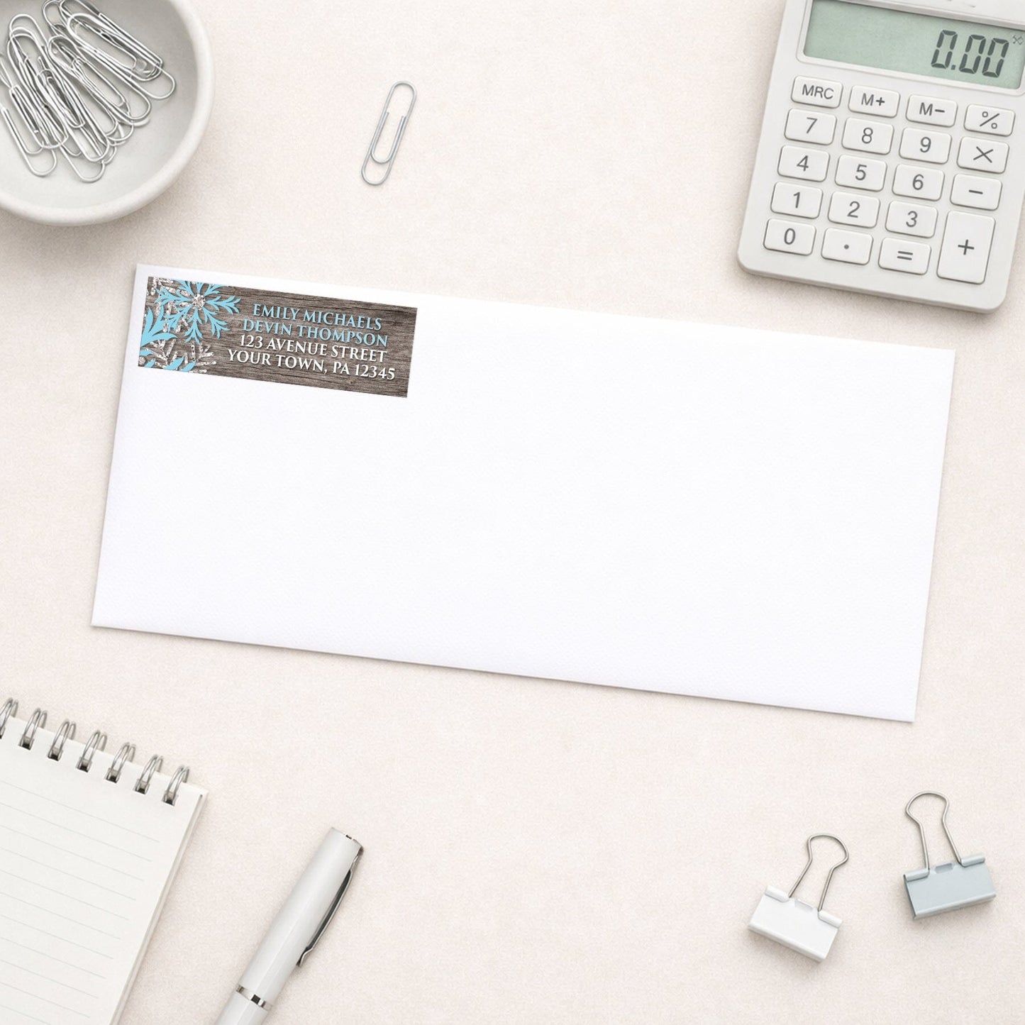 Rustic Winter Wood Blue Snowflake Address Label shown on a white envelope with everyday office supplies