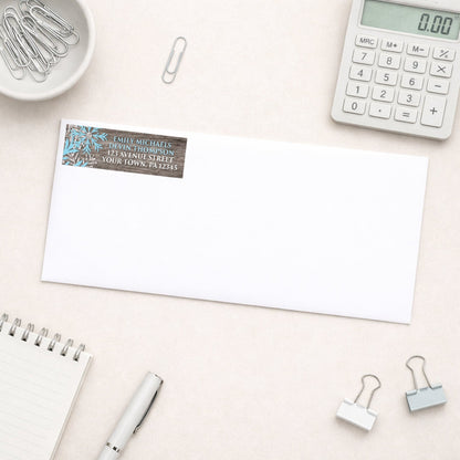 Rustic Winter Wood Blue Snowflake Address Label shown on a white envelope with everyday office supplies