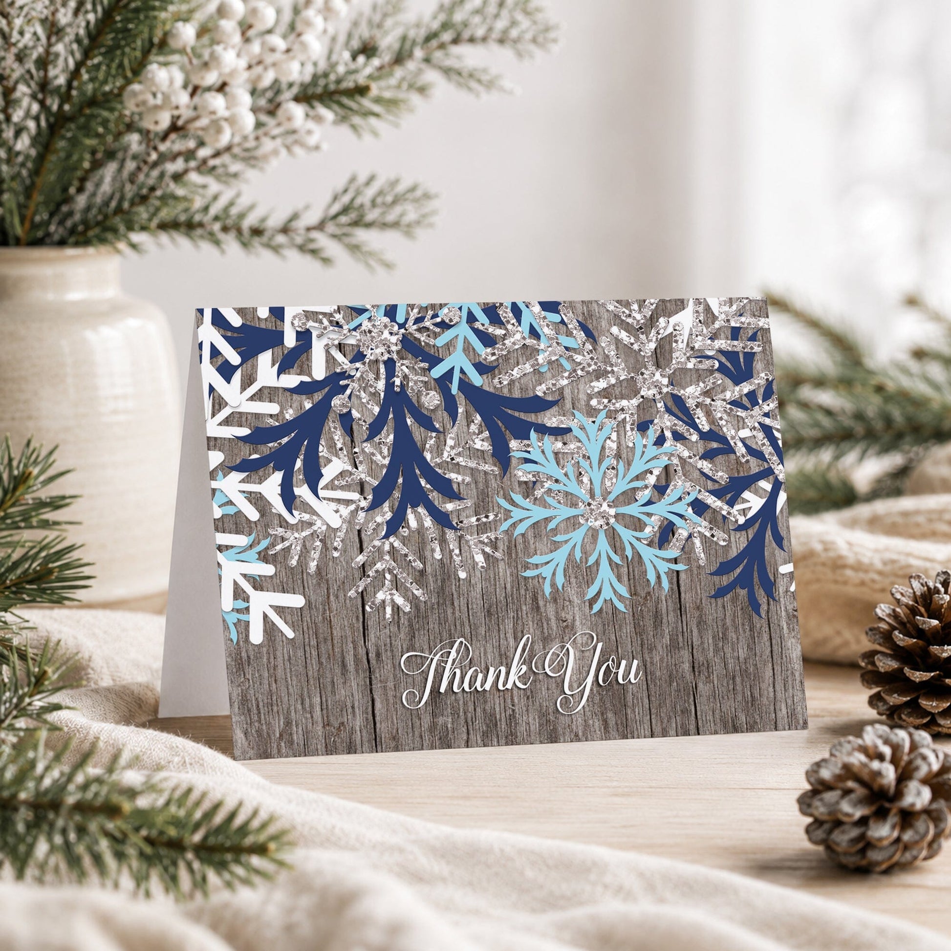 Rustic Winter Wood Navy Aqua Snowflake Thank You Card on a tabletop with a vase, winter greenery, and pine cones.