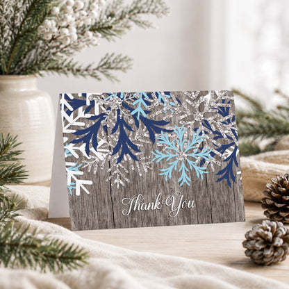 Rustic Winter Wood Navy Aqua Snowflake Thank You Card on a tabletop with a vase, winter greenery, and pine cones.