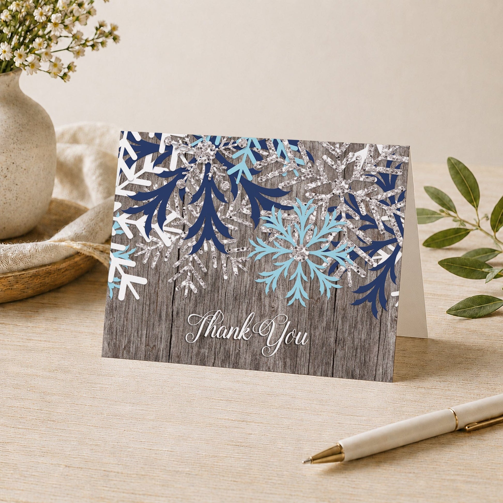 Rustic Winter Wood Navy Aqua Snowflake Thank You Card on a desk with a vase, plants, and a pen.