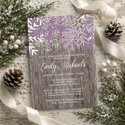 Rustic Winter Wood Purple Snowflake Bridal Shower Invitation surrounded by winter decorations.