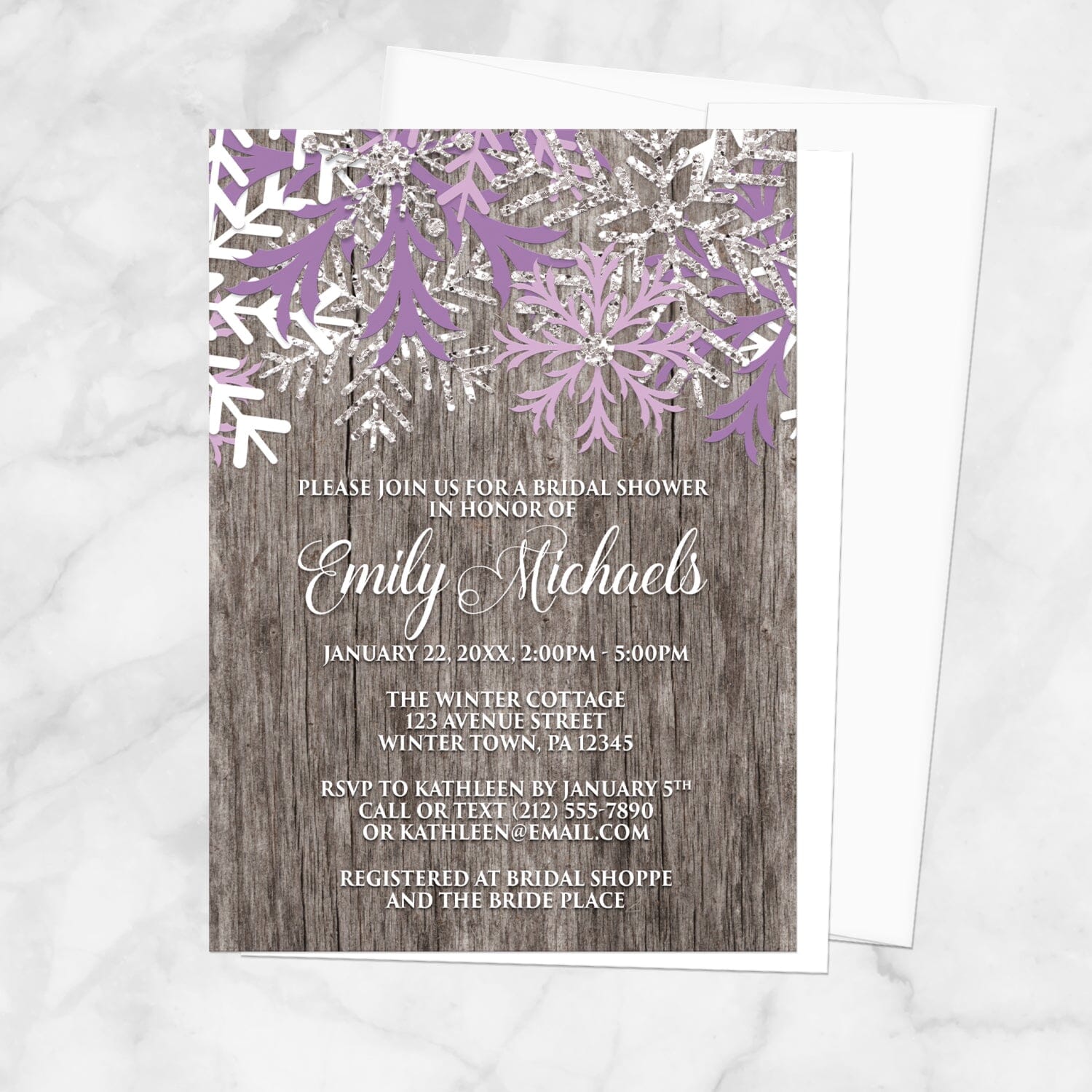 Bridal shower invitation with purple snowflakes on a wooden background, displayed with a white envelope on a marble surface
