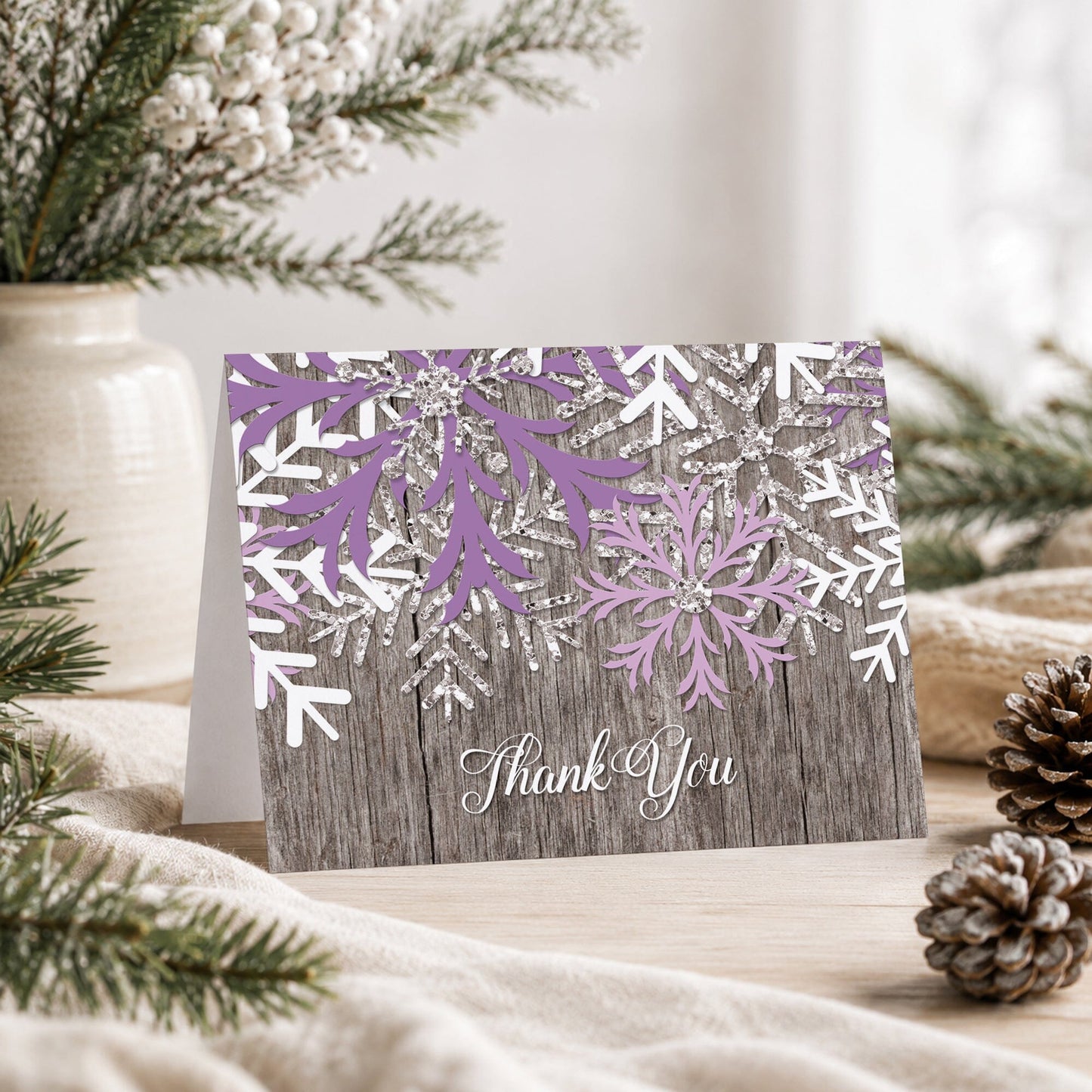 Rustic Winter Wood Purple Snowflake Thank You Card shown on a tabletop with a vase, winter greenery, and pine cones.