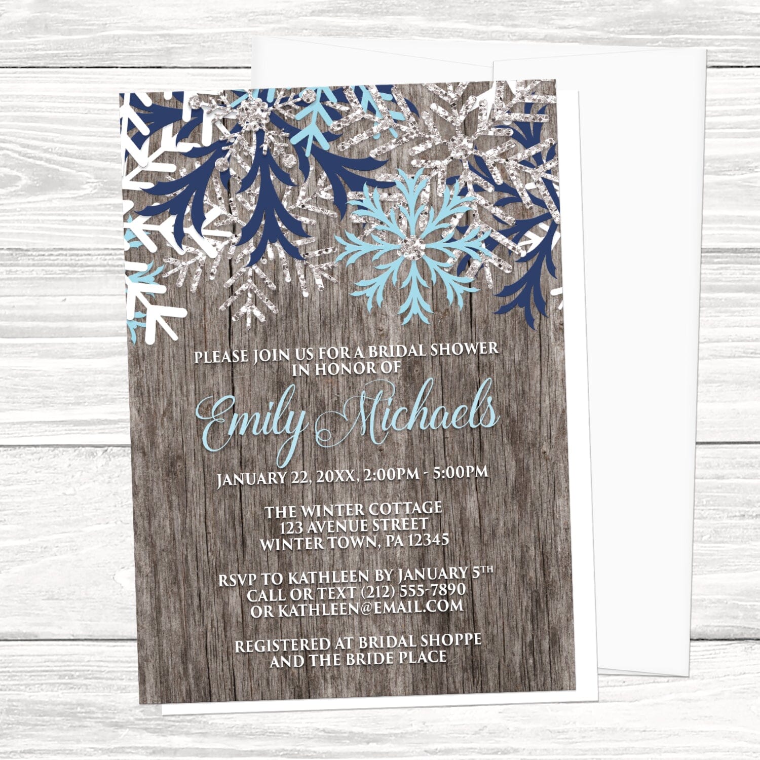 Rustic Winter Wood Navy Aqua Snowflake Bridal Shower Invitation shown on a light wood surface with a white envelope.