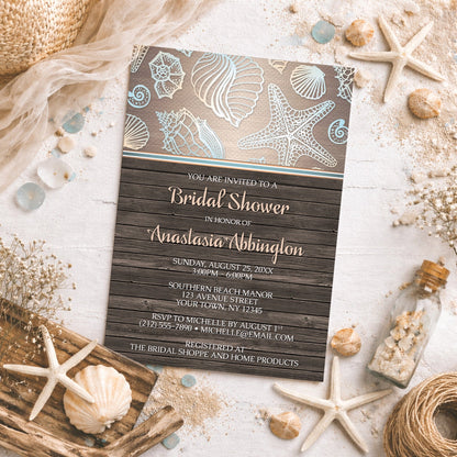 Rustic Wood Beach Seashell Bridal Shower Invitation shown on a rough surface with shells, sand, and other coastal decor.