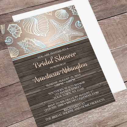 Rustic Wood Beach Seashell Bridal Shower Invitation shown at an angle on a wooden surface with a white envelope.
