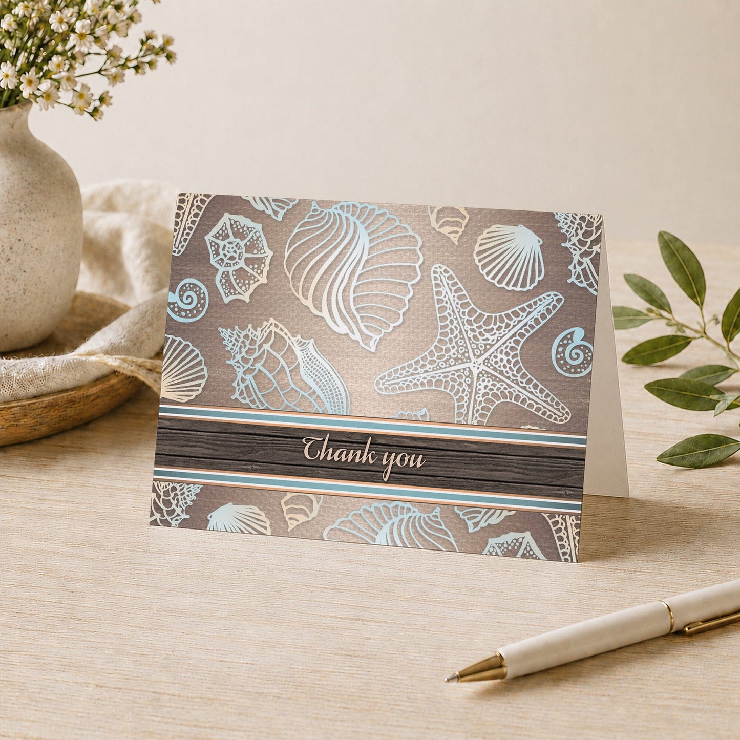 Rustic Wood Beach Seashell Thank You Card shown on a desk with a vase, plants, and a pen.