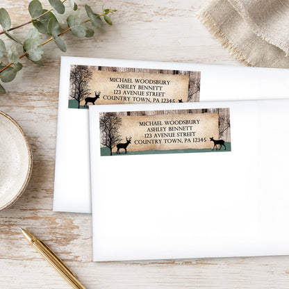 Address labels with deer design on a wooden surface with eucalyptus leaves and a pen.
