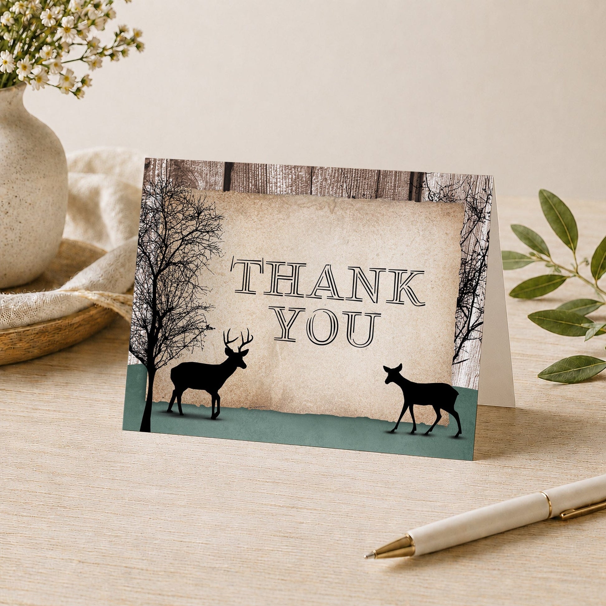 Rustic Woodsy Deer Thank You Card shown on a table with a pen, vase, and plants.
