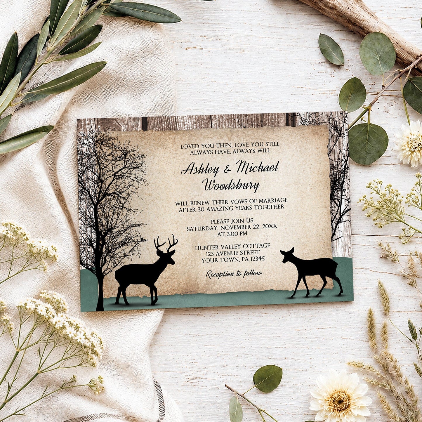 Rustic Woodsy Deer Vow Renewal Invitation shown on a light wooden surface with spring and summer plants.