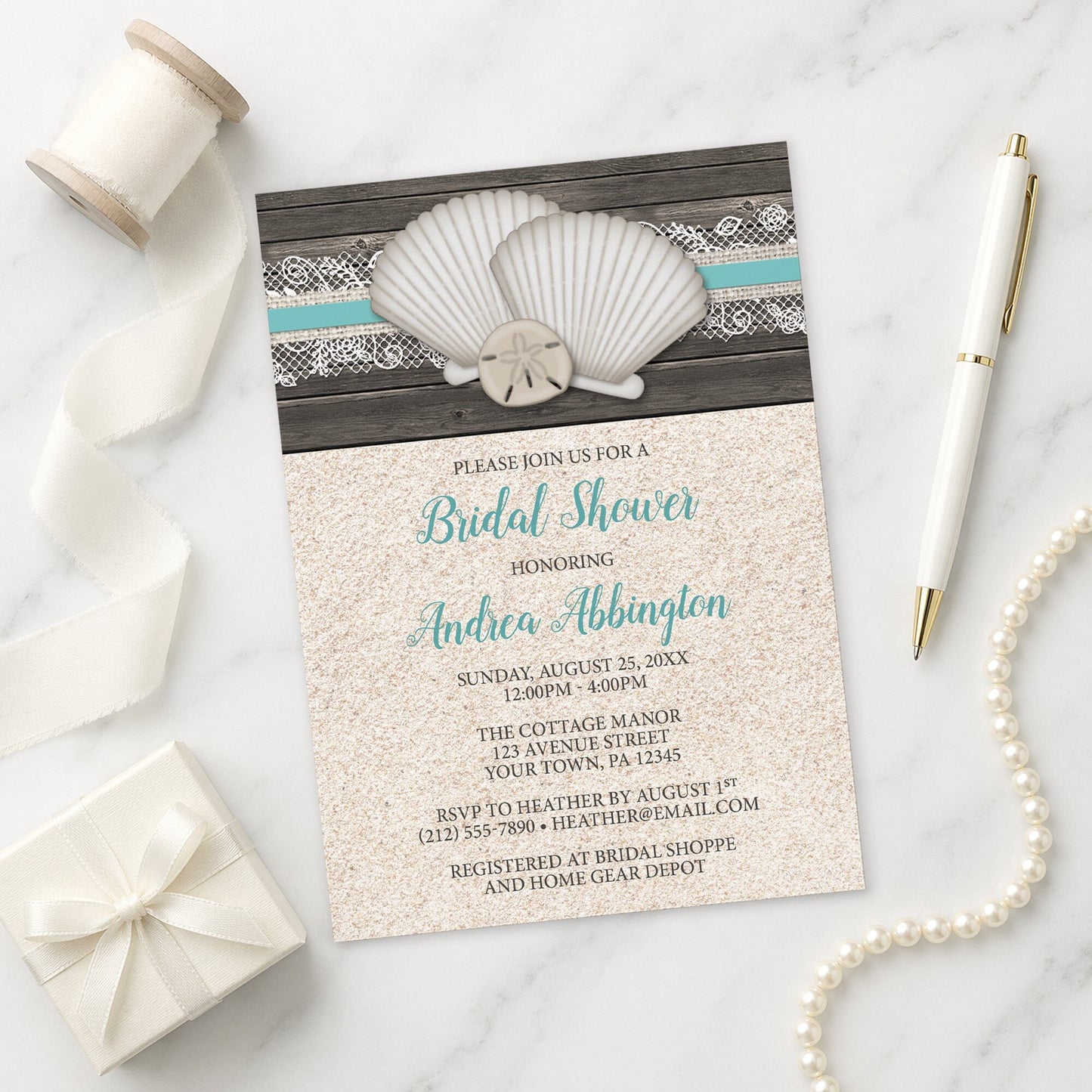 Beach-themed bridal shower invitation with shells, sand, and lace on a marble surface.