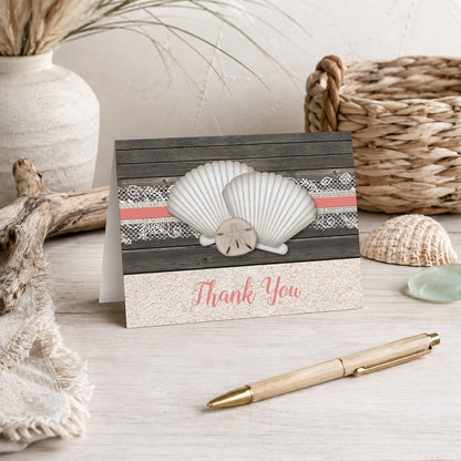 Seashell Lace Wood and Sand Coral Beach Thank You Card shown on a beach house tabletop with coastal decor and a pen.