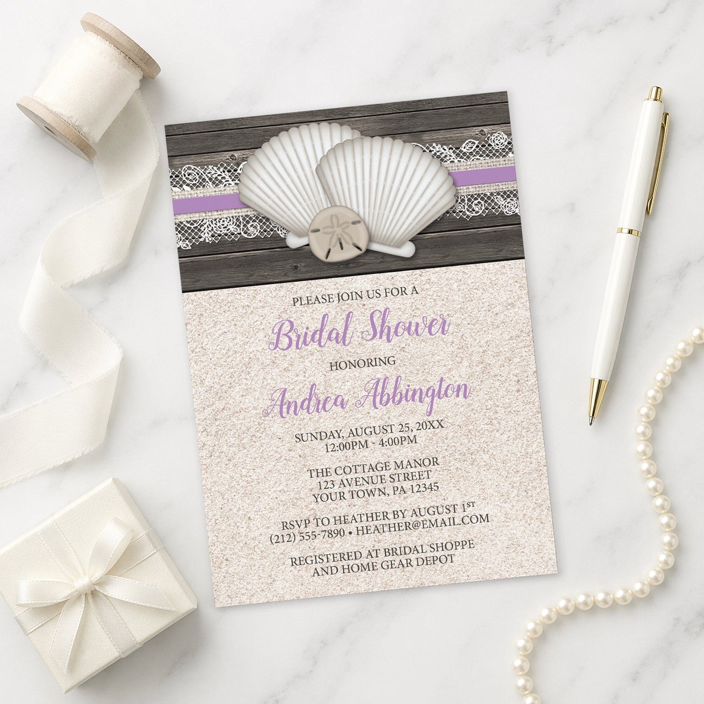Seashell Lace Wood and Sand Purple Beach Bridal Shower Invitation on a marble surface with a white gift box, pen, ribbon, and pearls.