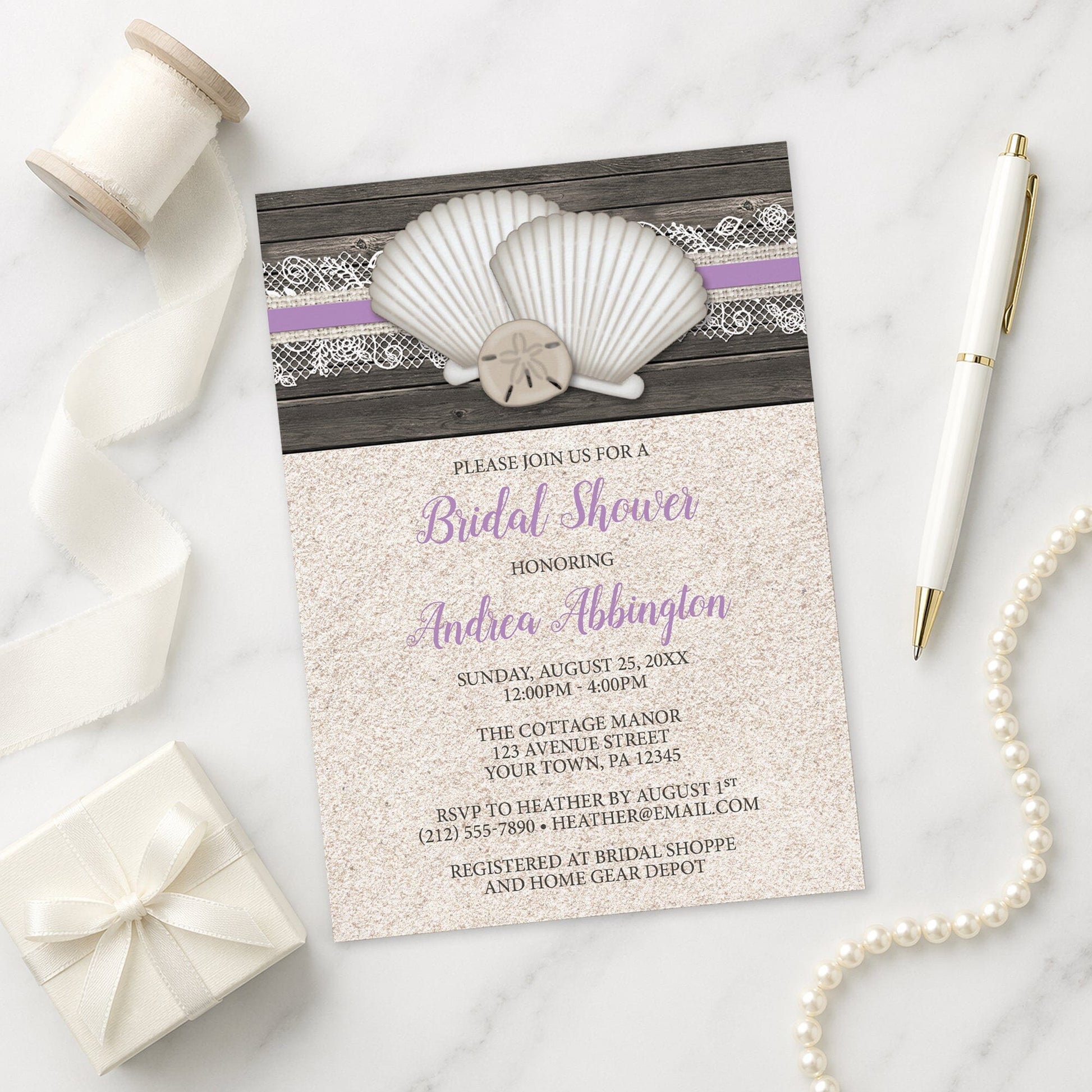 Seashell Lace Wood and Sand Purple Beach Bridal Shower Invitation on a marble surface with a white gift box, pen, ribbon, and pearls.