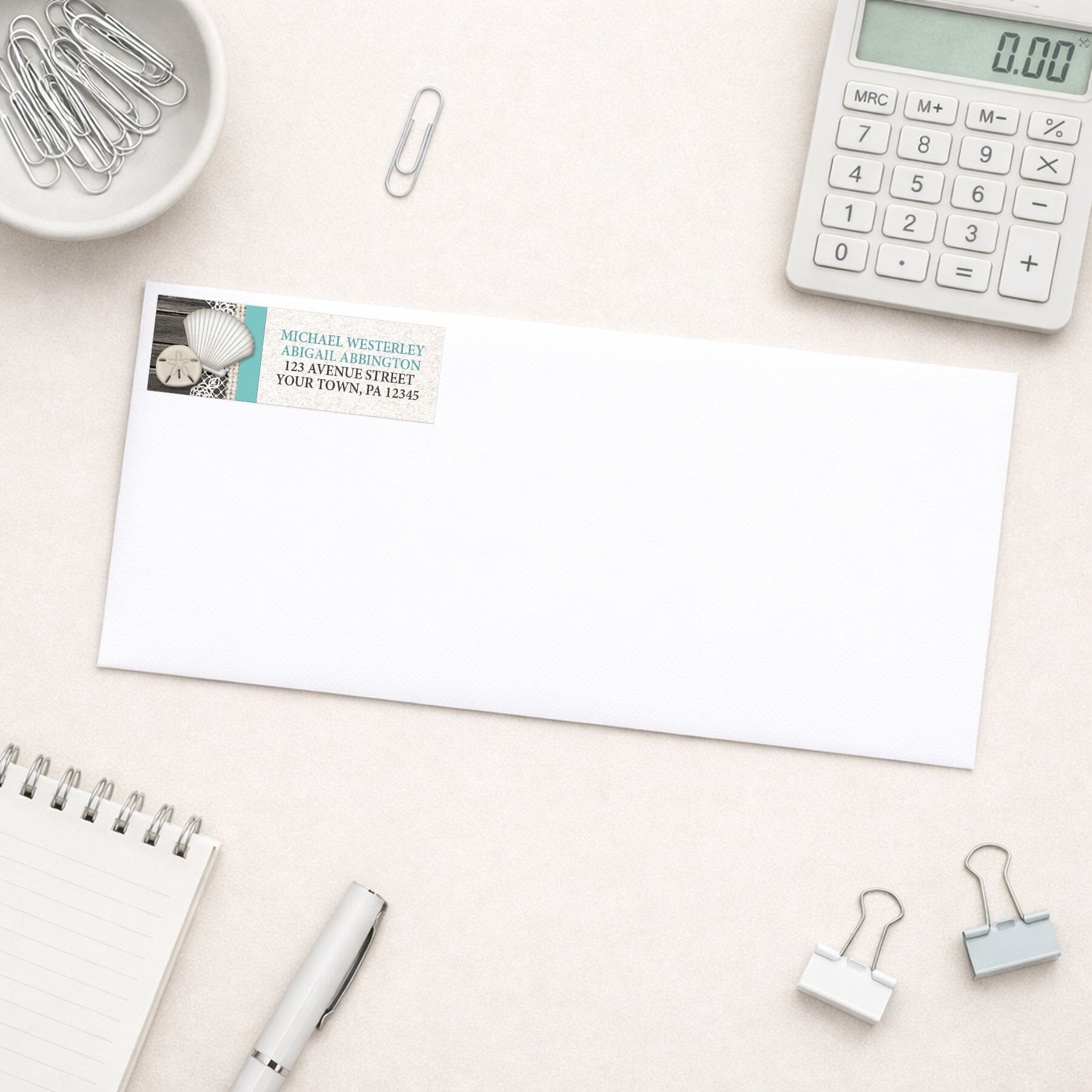 Seashell Lace Wood and Sand Teal Beach Address Label shown on a white envelope with everyday office supplies