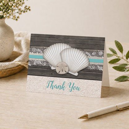 Seashell Lace Wood and Sand Teal Beach Thank You Card shown on a desk with a vase, plants, and a pen.
