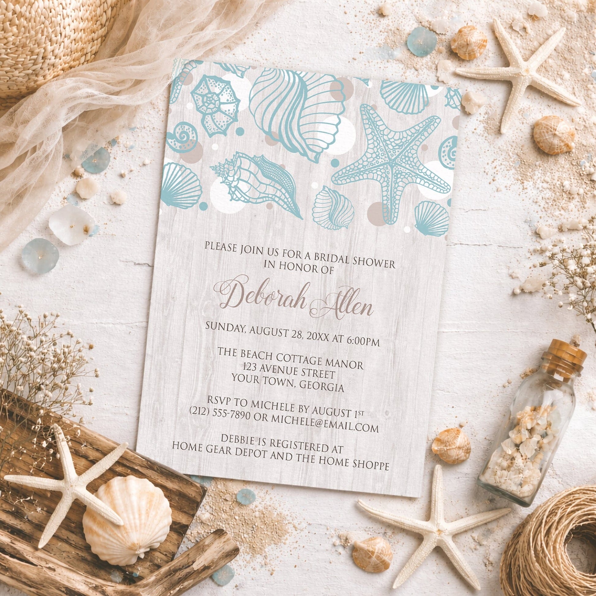 Seashell Whitewashed Wood Beach Bridal Shower Invitation on a rough surface with seashells, drift wood, sand, and other beach decor.