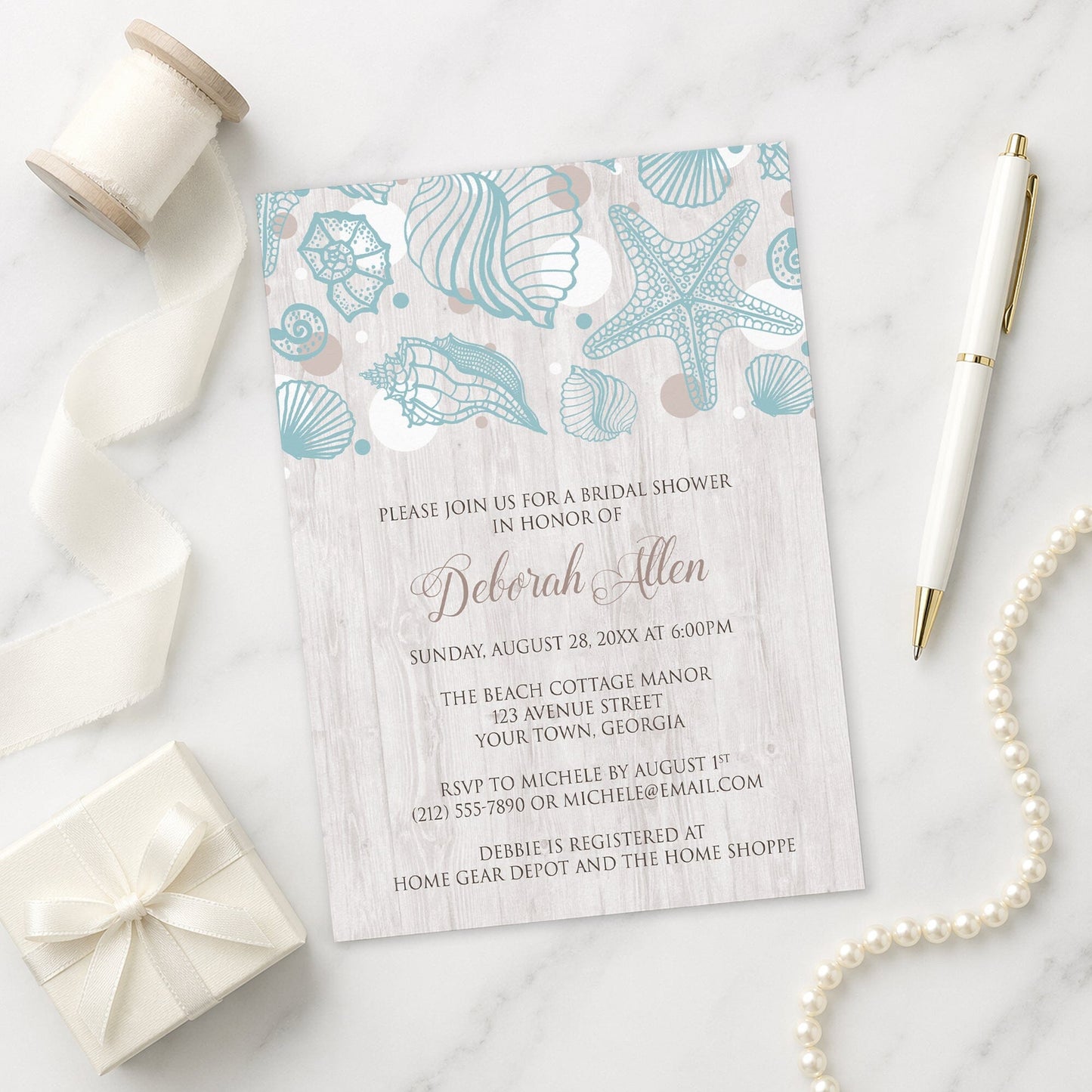 Seashell Whitewashed Wood Beach Bridal Shower Invitation on a marble surface with a white gift box, pen, ribbon, and pearls.