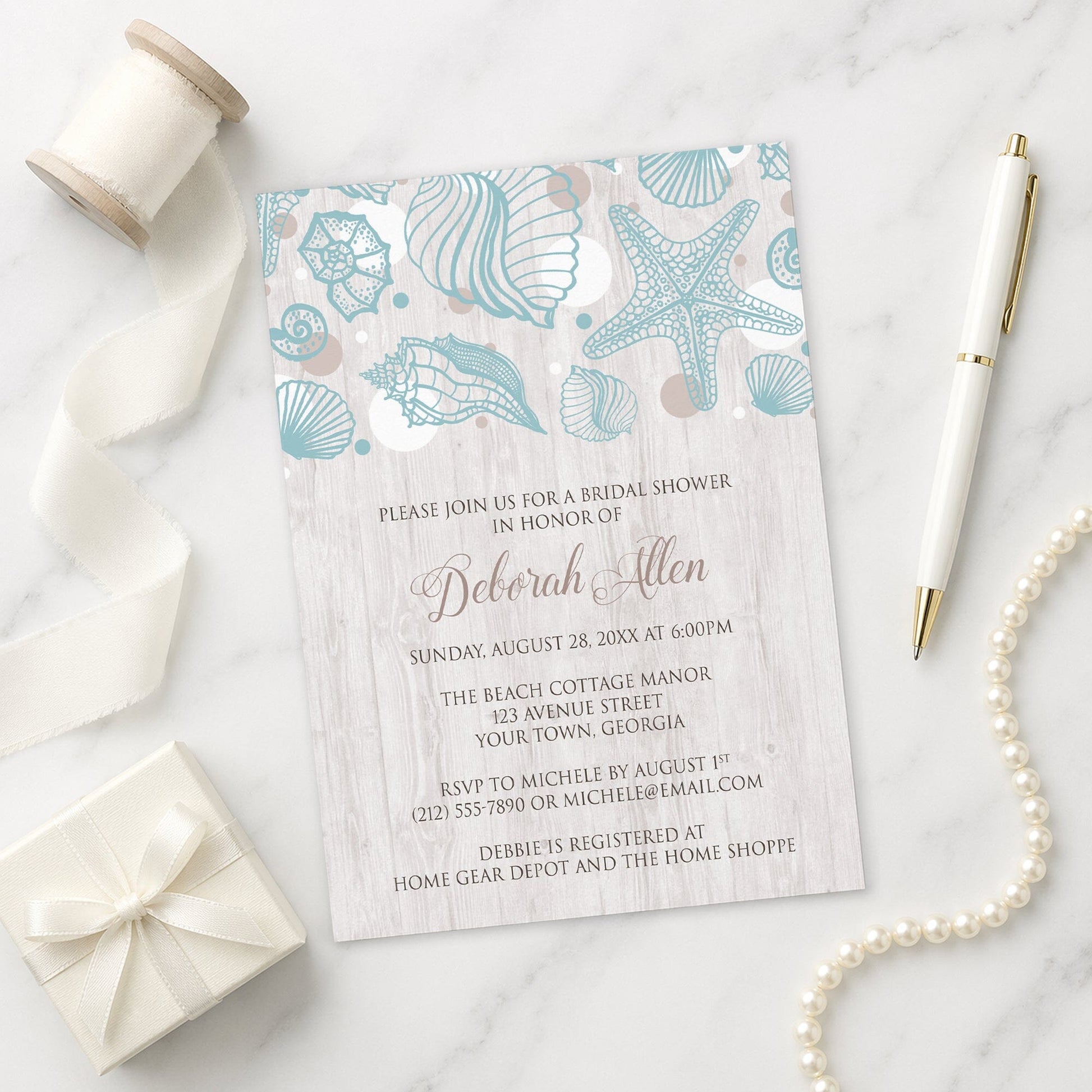 Seashell Whitewashed Wood Beach Bridal Shower Invitation on a marble surface with a white gift box, pen, ribbon, and pearls.