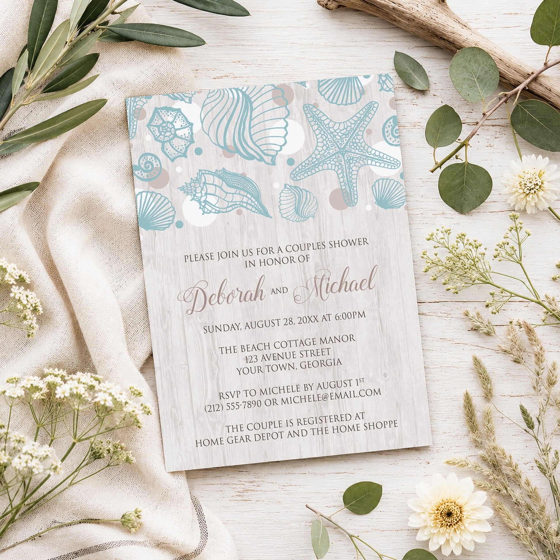 Seashell Whitewashed Wood Beach Couples Shower Invitation shown on a light wooden surface with summer plants.