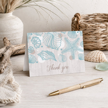 Seashell Whitewashed Wood Beach Thank You Card shown on a tabletop with a vase, beach house decor, and a pen.