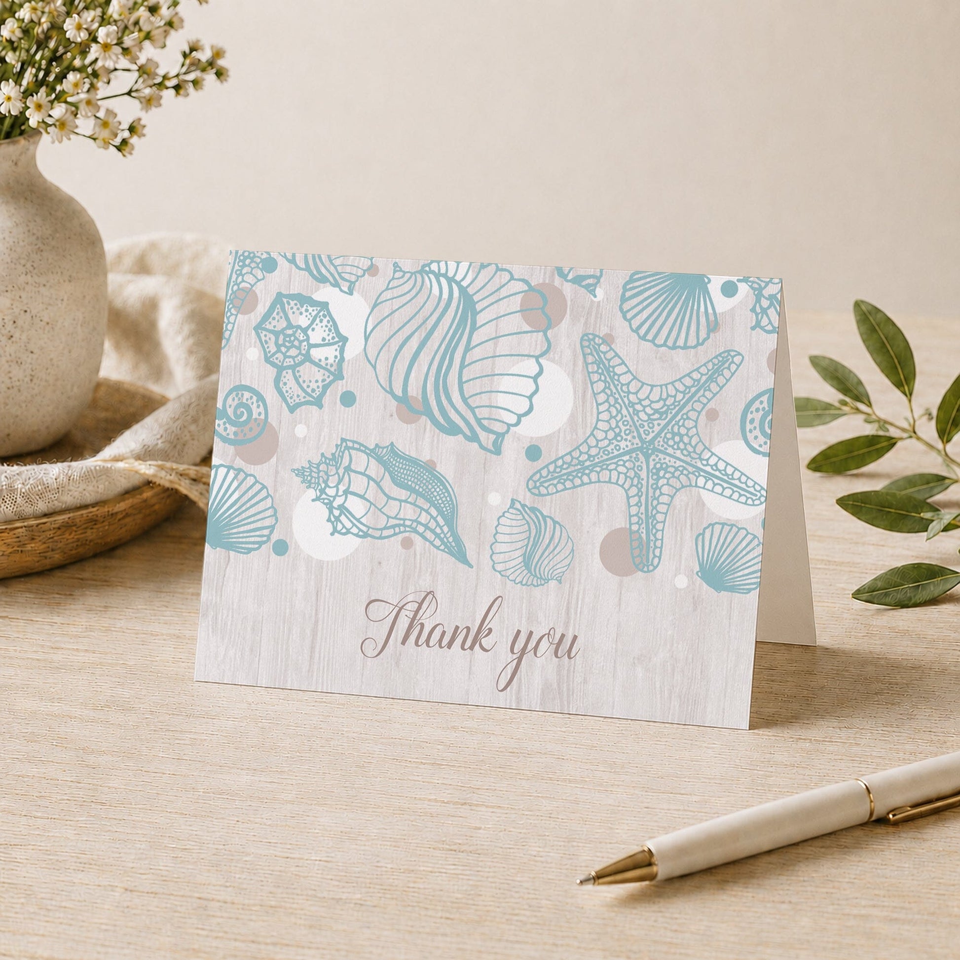 Seashell Whitewashed Wood Beach Thank You Card shown on a tabletop with a vase, plants, and a pen.