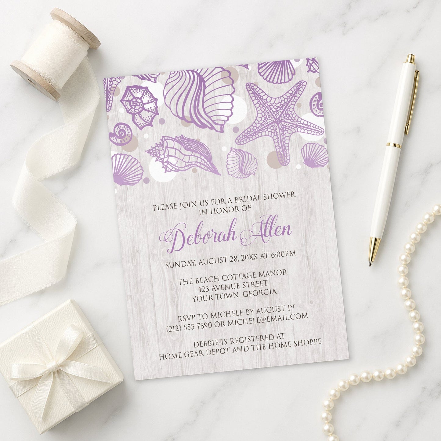 Seashell Whitewashed Wood Purple Beach Bridal Shower Invitation on a marble surface with ribbon, gift, and pen.